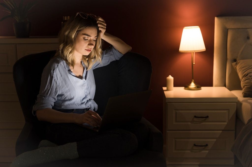 how to stop overthinking at night - woman sitting awake late at night with laptop looking stressed
