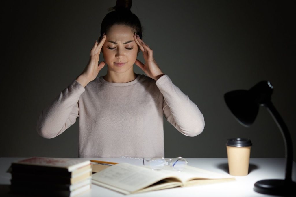 Woman holding her head at night showing stress and overthinking while learning how to rewire your brain for positivity